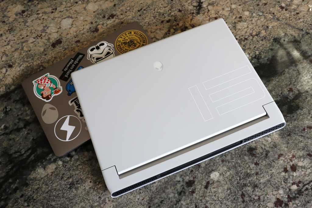 An Alienware laptop sits atop a MacBook Pro