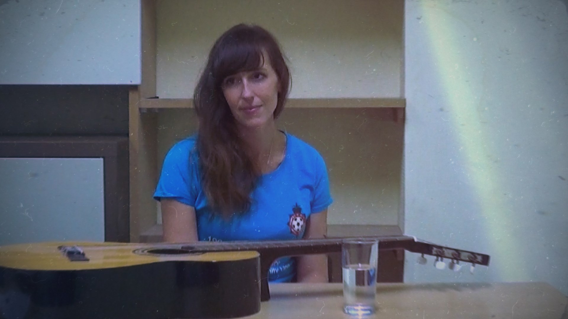 A woman with a guitar on a table in front of her