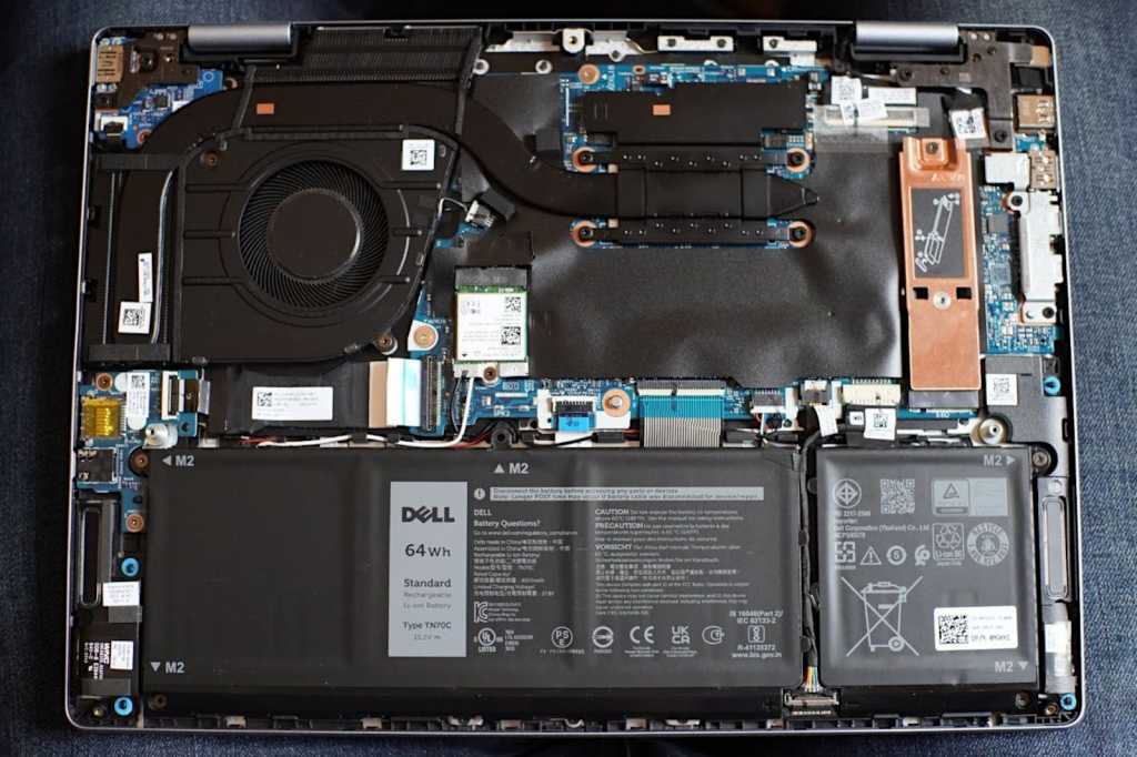 Dell laptop opened with internal components exposed including battery and SSD